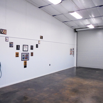 Clean garage with awards, hose reel, and roll-up door - Double Nickel Nine Motorsports from Del Rey, CA