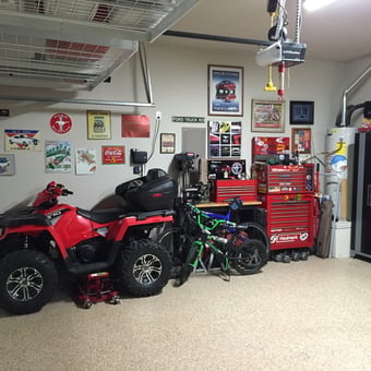 Organized garage with tool chests, ATV, bikes, and wall signs - Steve's Stangs from Hickory Creek, Tx