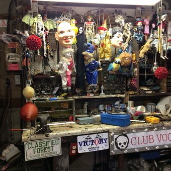 Eclectic Garage Workbench with Dolls, Tools, and Signs - Scary Garage