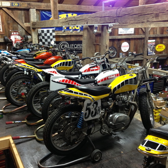 Vintage Yamaha Motorcycles and Racing Gear in Rustic Garage - Team Slideways
