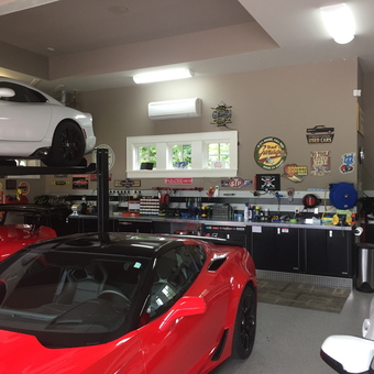 Organized Garage With Car Lift, Cabinets, and Wall Signs - Anonymous
