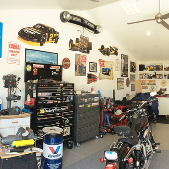Organized garage with tool chests, wall signs, and vehicles - Ray