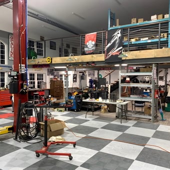 Organized garage with car lift, tool chests, and workbenches - Thomas