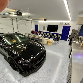 Modern Garage With Black Sports Car and Stainless Cabinets - Bruce
