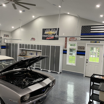 Organized garage with cabinets, wall signs, and classic car - James from Huntington, NY