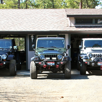 Garage with Multiple Jeeps, Off-Road Vehicles, and Accessories - Anonymous