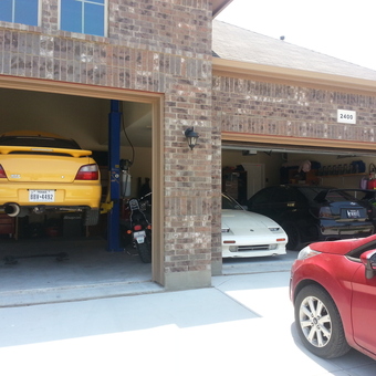 Organized garage with car lift, storage shelves, and sports cars - Squidz from Fort Worth, TX