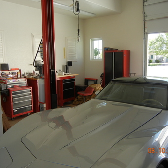 Organized garage with car lift, tool chests, and cabinets - Anonymous