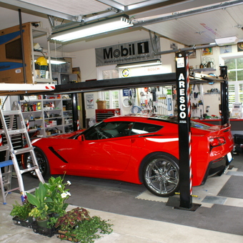 Organized garage with car lift, workbench, and red sports car - jerry carguy from pinckney, MI