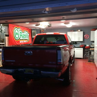 Organized garage with cabinets, workbench, and red GMC truck - O'Reillys Garage from Soldotna, AK