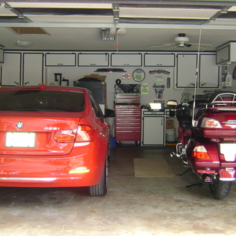 Organized garage with red BMW, motorcycle, cabinets, and tool chest - CC Winger from Corpus Christi, TX