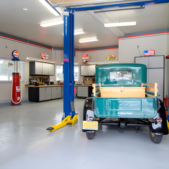 Organized garage with car lift, cabinets, and vintage signs - Ian from Denver, CO