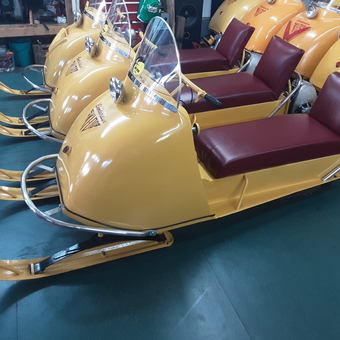 Vintage yellow snowmobiles with red seats in garage - Skidooman from Orillia